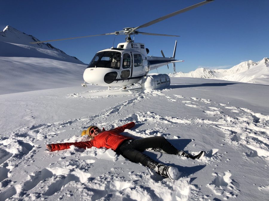 wanaka helicopter trip with aspiring helicopters girl in red jacket lying in snow